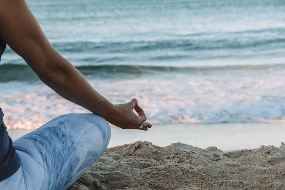 Hands resting in a gentle meditative gesture within a sacred healing space