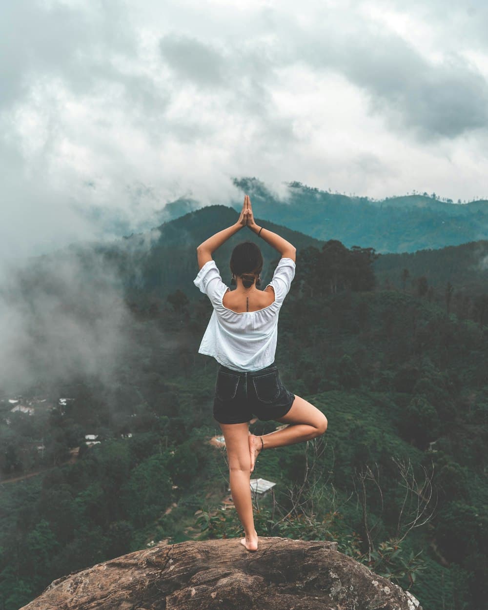 A person meditating in misty mountains at dawn